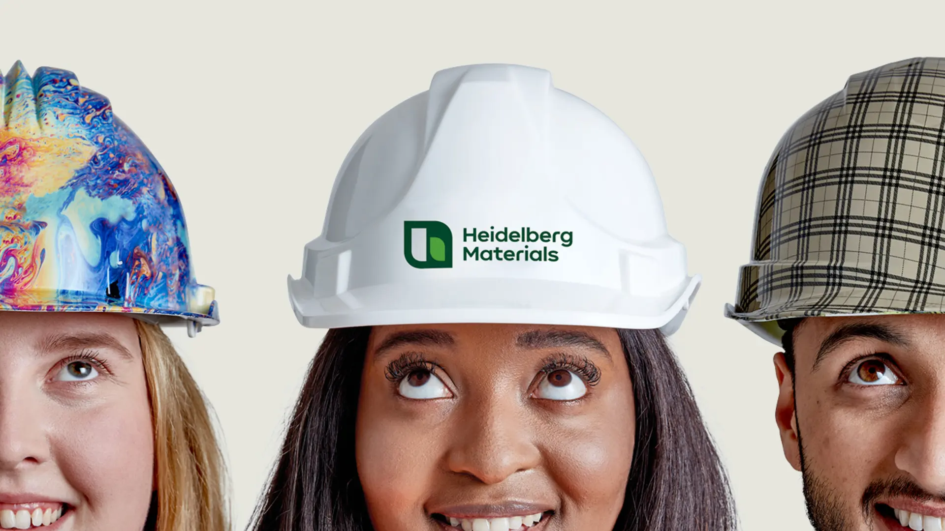 Three construction hard hats are displayed side by side: a colorful tie-dye patterned hard hat on the left, a plain white hard hat with a logo in the center, and a plaid-patterned hard hat on the right.